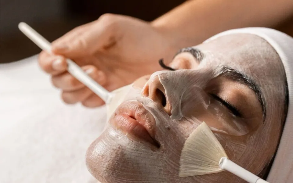 A therapist applies a facial mask with a fan brush